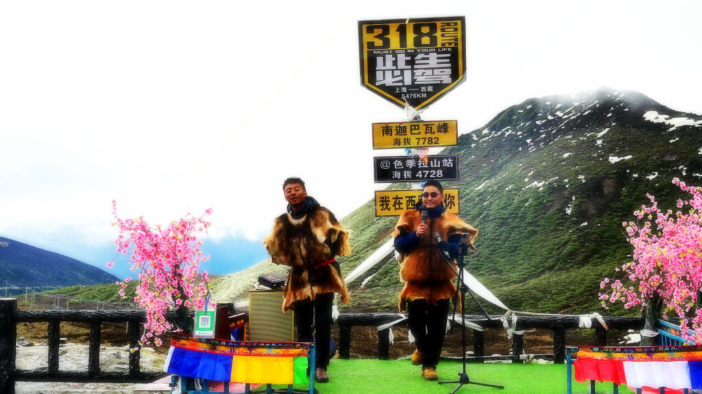 2 male Tibetian singers are singing for public.