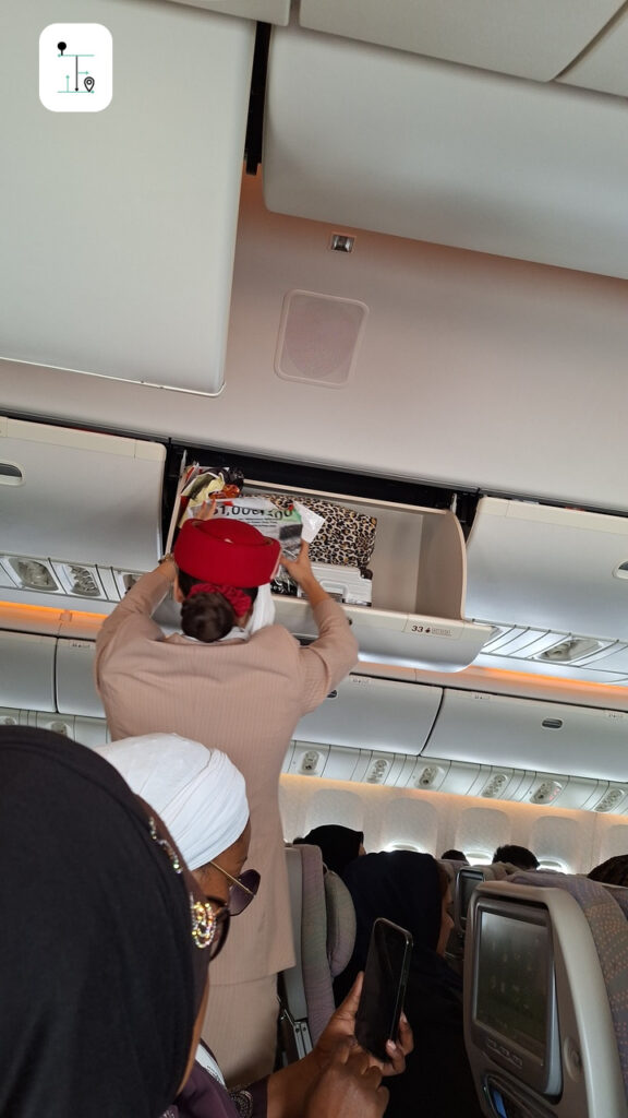 Emirates flight attendant is managing the bags inside the overhead locker.